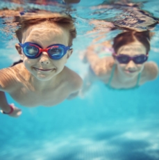 Happy kids swimming underwater in pool
